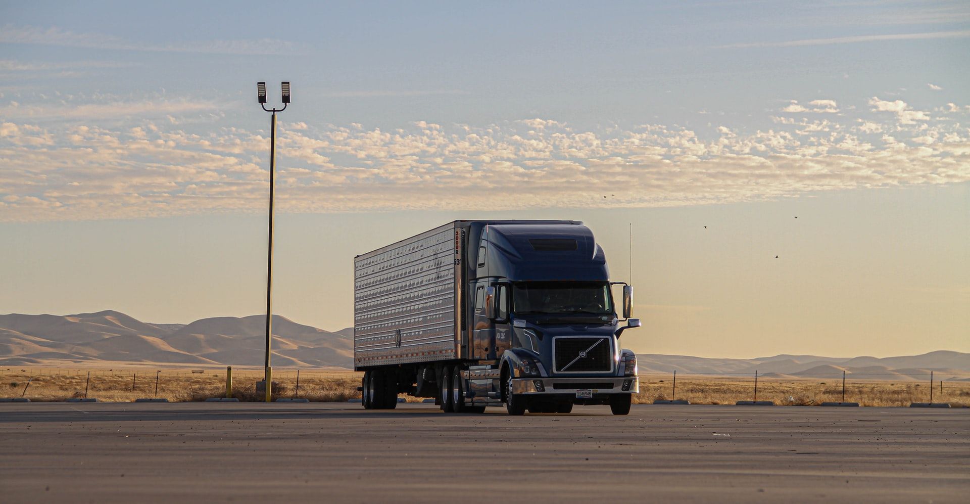 Semi-truck and trailer parked on an open lot at dusk